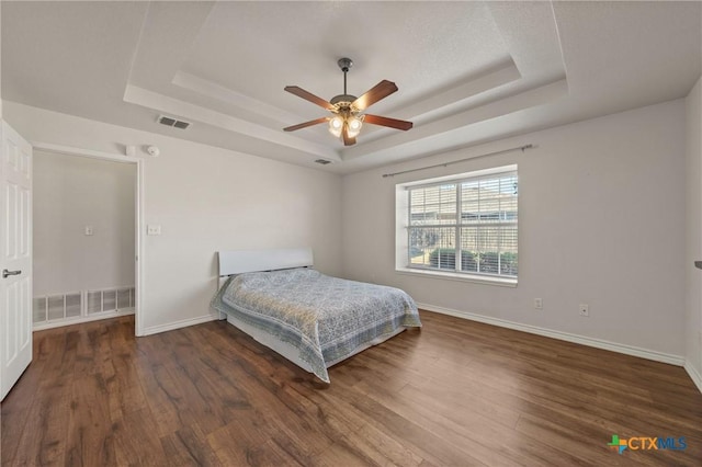 bedroom with a raised ceiling, ceiling fan, and dark hardwood / wood-style floors