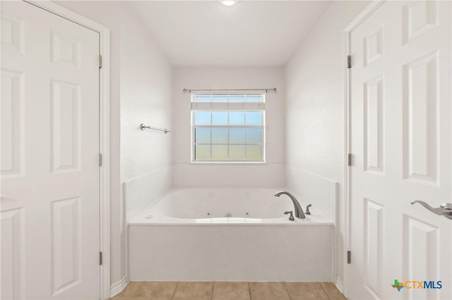 bathroom with a tub to relax in and tile patterned flooring