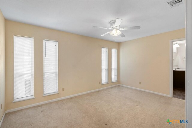 unfurnished bedroom with visible vents, light colored carpet, baseboards, and multiple windows