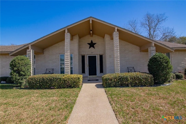 property entrance featuring a yard and brick siding