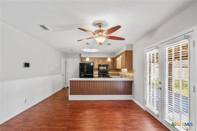 kitchen with black appliances, a peninsula, dark wood-style flooring, and visible vents