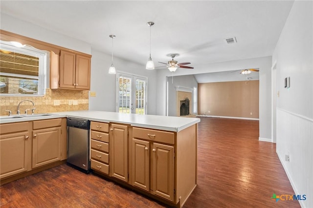 kitchen featuring a brick fireplace, dishwasher, light countertops, a peninsula, and a sink