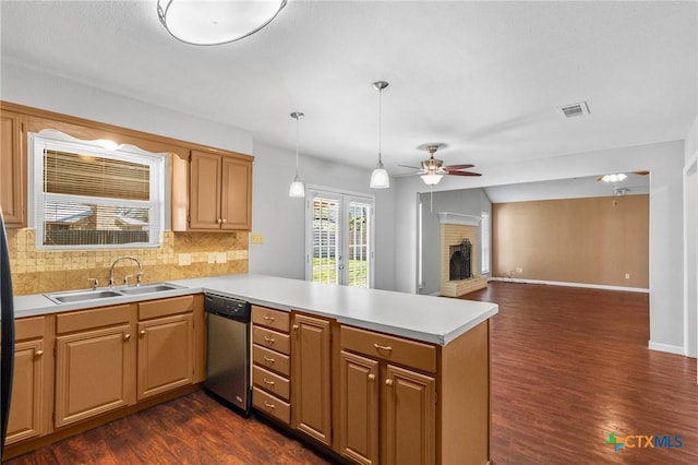 kitchen featuring a sink, a peninsula, a fireplace, light countertops, and dishwasher