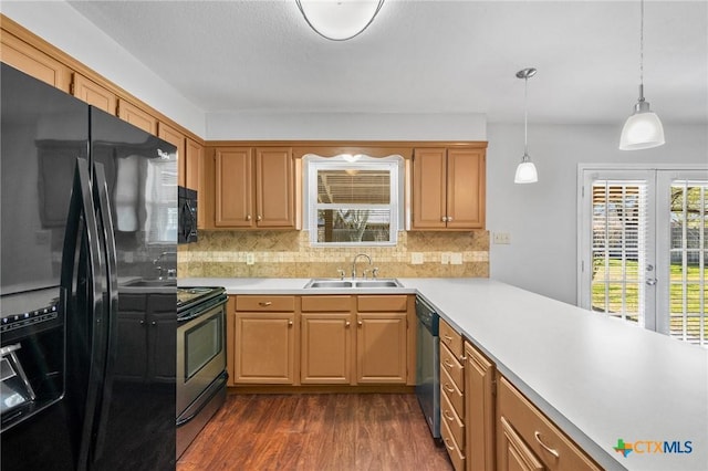 kitchen with a sink, black appliances, dark wood-style floors, and light countertops