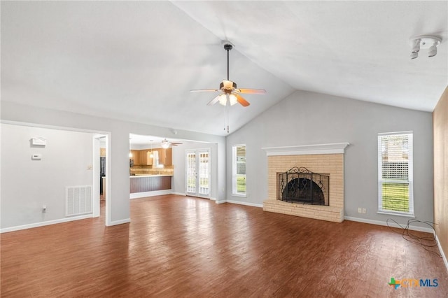 unfurnished living room with wood finished floors, visible vents, a fireplace, ceiling fan, and vaulted ceiling