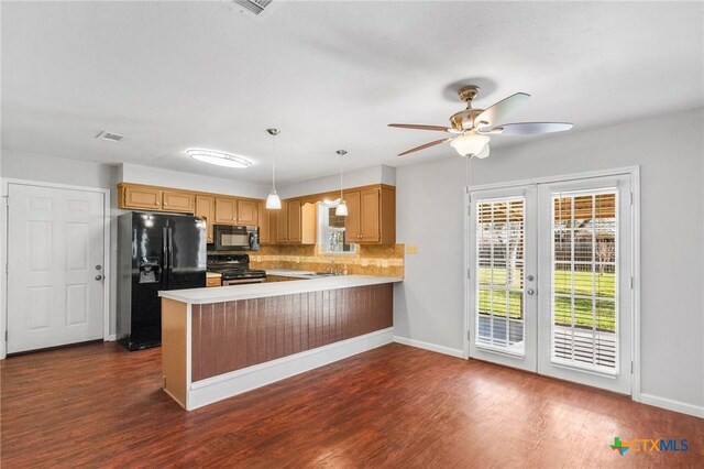 kitchen featuring a peninsula, plenty of natural light, dark wood-style flooring, decorative backsplash, and black appliances