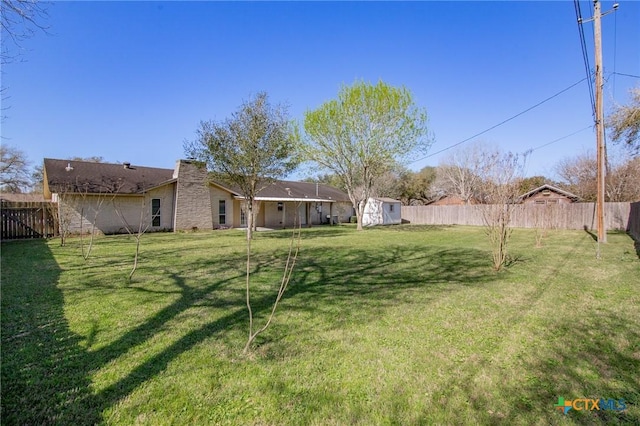 view of yard with a storage unit, a fenced backyard, and an outdoor structure