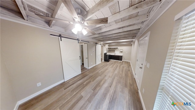 interior space with light wood-type flooring, a barn door, and ceiling fan