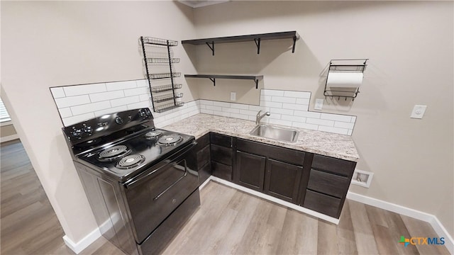 kitchen featuring sink, dark brown cabinets, black range with electric stovetop, light wood-type flooring, and decorative backsplash