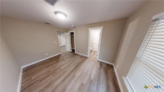 unfurnished bedroom featuring connected bathroom and light hardwood / wood-style flooring