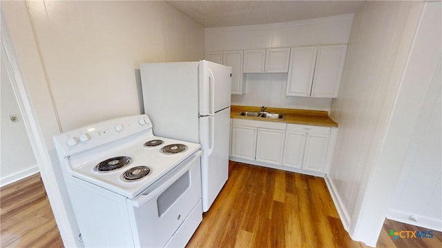 kitchen featuring white appliances, sink, hardwood / wood-style flooring, and white cabinets