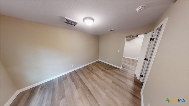 spare room with light hardwood / wood-style floors and a textured ceiling