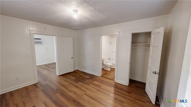 unfurnished bedroom featuring a textured ceiling, ensuite bath, and dark hardwood / wood-style floors