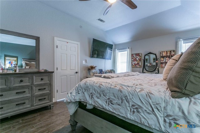 bedroom featuring ceiling fan, multiple windows, dark hardwood / wood-style flooring, and vaulted ceiling