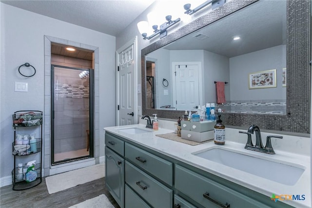 bathroom with hardwood / wood-style flooring, a textured ceiling, a shower with shower door, and vanity