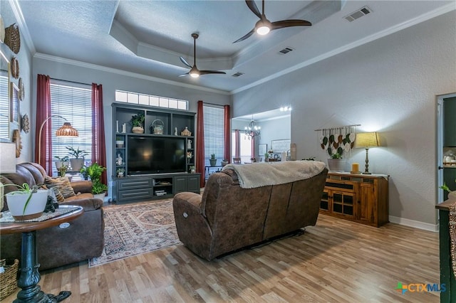 living room featuring ceiling fan with notable chandelier, hardwood / wood-style floors, a textured ceiling, a tray ceiling, and crown molding