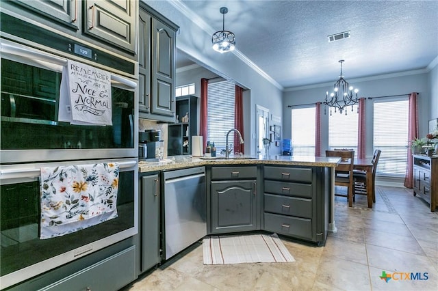 kitchen with a textured ceiling, appliances with stainless steel finishes, an inviting chandelier, hanging light fixtures, and crown molding