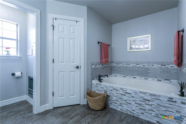 bathroom with a relaxing tiled tub, a textured ceiling, and hardwood / wood-style floors