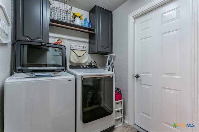 clothes washing area featuring washing machine and dryer, cabinets, and a textured ceiling