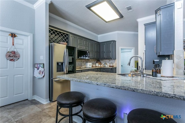 kitchen with appliances with stainless steel finishes, sink, ornamental molding, kitchen peninsula, and light stone counters