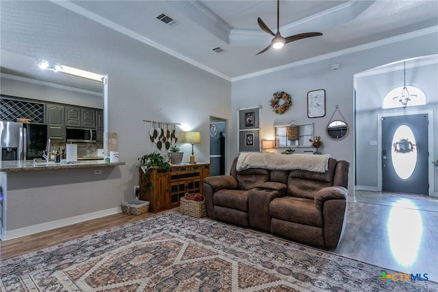 living room with ceiling fan, ornamental molding, hardwood / wood-style floors, and a tray ceiling