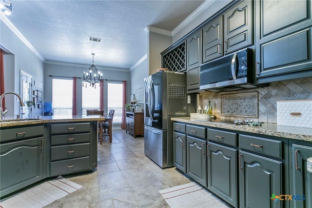 kitchen with appliances with stainless steel finishes, a notable chandelier, a textured ceiling, pendant lighting, and sink