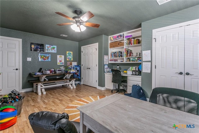 office with a textured ceiling, ceiling fan, and light hardwood / wood-style flooring