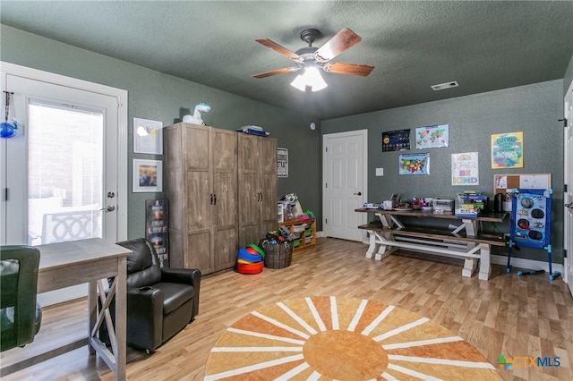 playroom with ceiling fan, hardwood / wood-style floors, and a textured ceiling