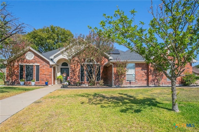 ranch-style home with a front yard and solar panels