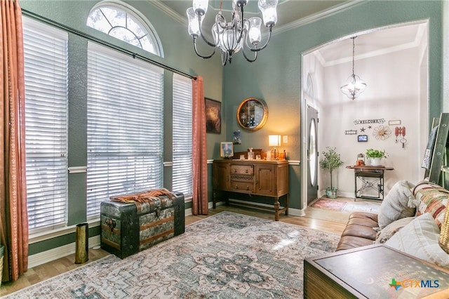 living room featuring an inviting chandelier, ornamental molding, and light hardwood / wood-style floors