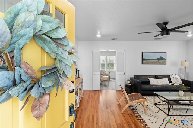 living room featuring visible vents, light wood-style floors, and ceiling fan