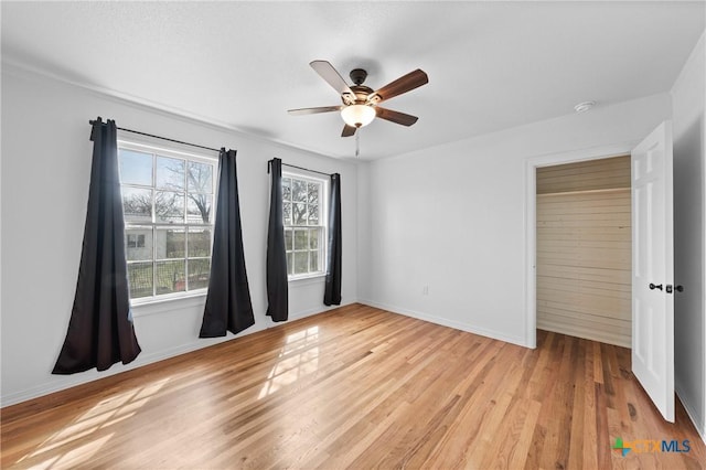 unfurnished bedroom with ceiling fan, baseboards, and light wood-style flooring