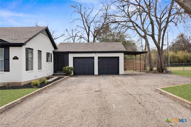 view of home's exterior with brick siding, driveway, an attached garage, and fence