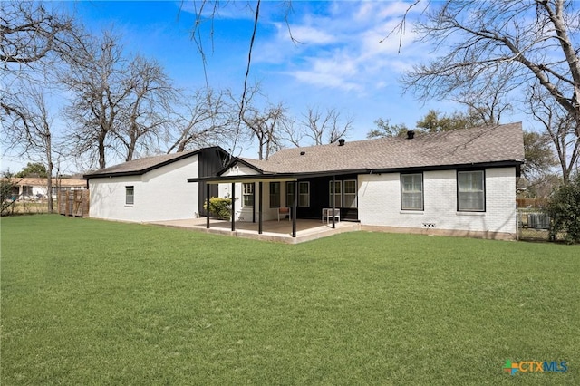 back of property with a patio area, a lawn, brick siding, and fence