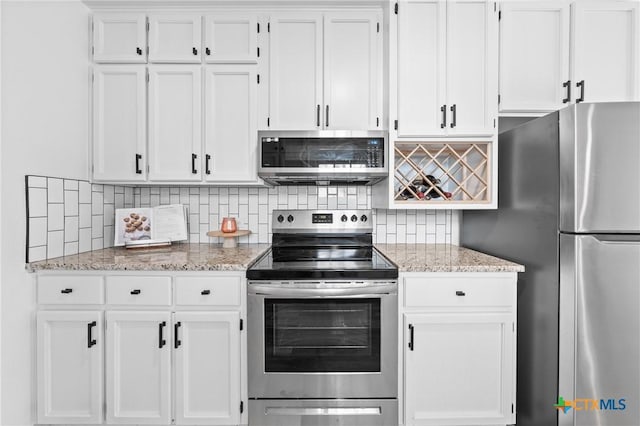 kitchen with decorative backsplash, light stone countertops, appliances with stainless steel finishes, and white cabinetry