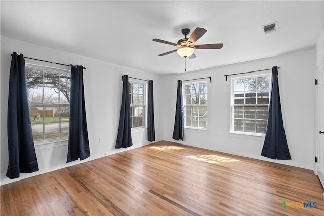 empty room featuring visible vents, baseboards, ceiling fan, and wood finished floors