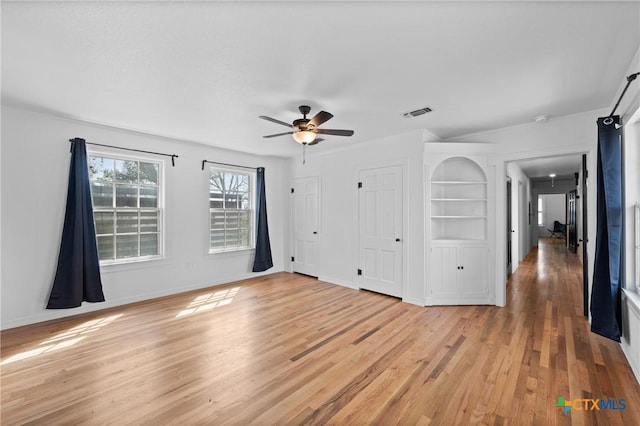 unfurnished bedroom featuring visible vents, baseboards, two closets, and light wood-style flooring