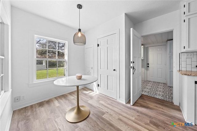 unfurnished dining area featuring light wood-type flooring and baseboards