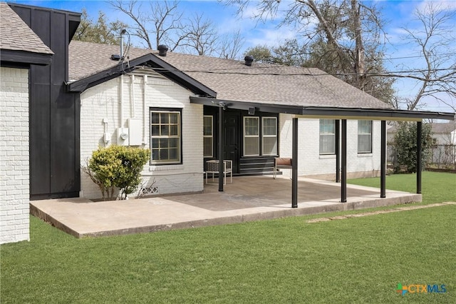 back of house with a yard, brick siding, entry steps, and a shingled roof