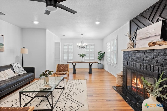 living room with a textured ceiling, a fireplace, light wood-type flooring, and a healthy amount of sunlight