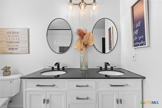 full bathroom featuring a sink, toilet, and double vanity