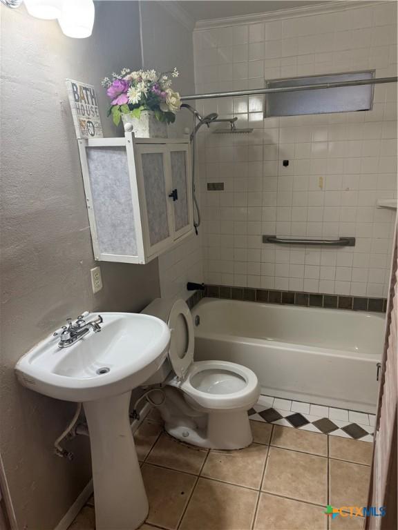 bathroom featuring crown molding, tiled shower / bath combo, tile patterned floors, and toilet