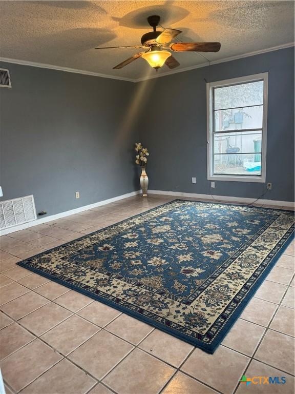 unfurnished room with ornamental molding, ceiling fan, tile patterned floors, and a textured ceiling