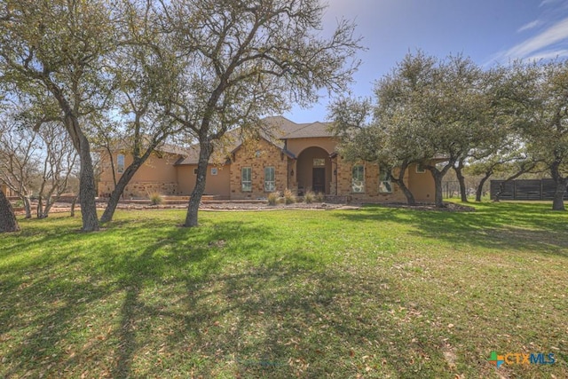 view of front of property featuring fence, a front lawn, and stucco siding