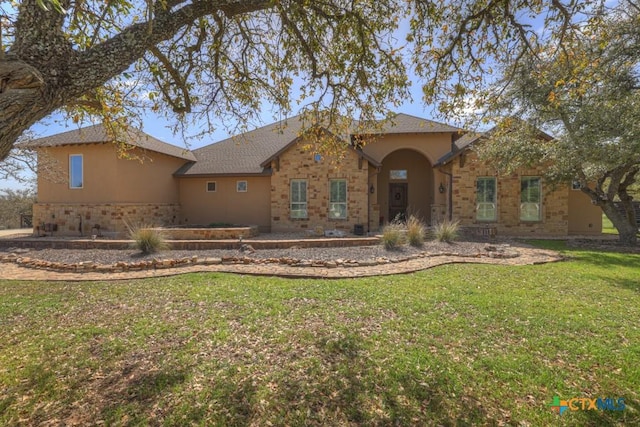 view of front of property featuring stucco siding, stone siding, and a front lawn