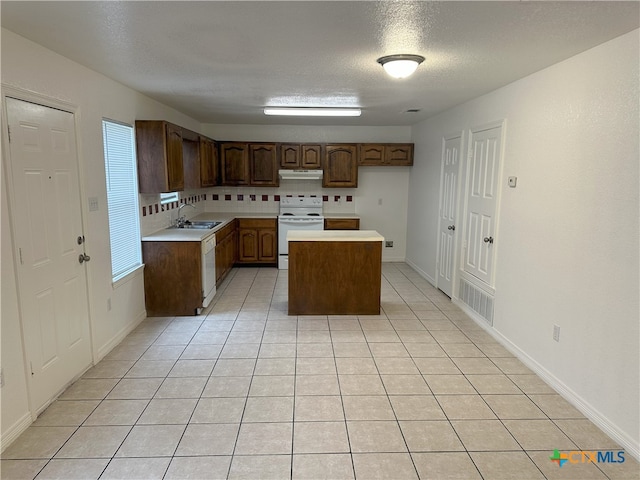 kitchen featuring white appliances, under cabinet range hood, a sink, a kitchen island, and light countertops