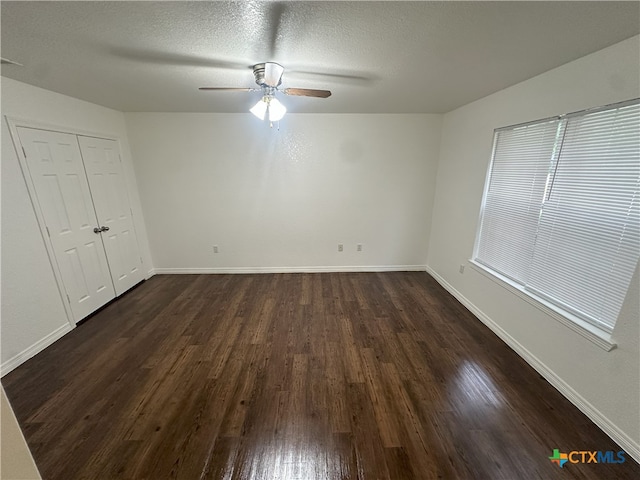 unfurnished bedroom featuring dark wood finished floors, baseboards, a textured ceiling, a ceiling fan, and a closet