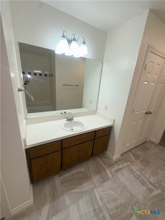 bathroom with vanity, a textured wall, a shower, and baseboards