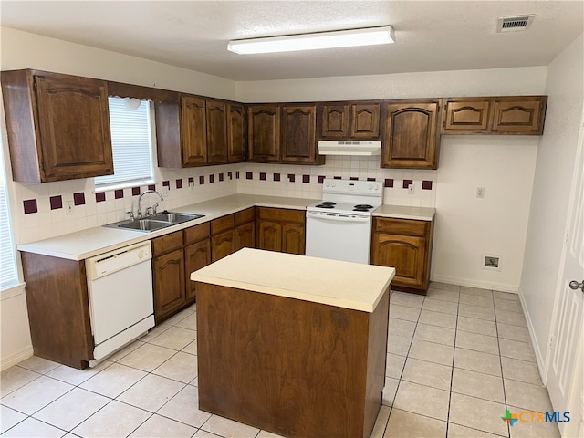 kitchen featuring white appliances, under cabinet range hood, a sink, and tasteful backsplash