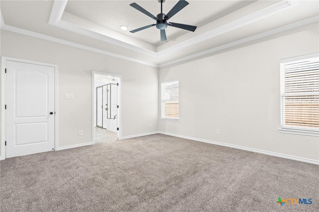 empty room featuring ornamental molding, light carpet, ceiling fan, and a tray ceiling